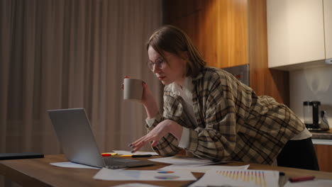 Beautiful-young-woman-working-on-laptop-computer-while-sitting-at-the-living-room-drinking-coffee.-Happy-casual-beautiful-woman-working-on-a-laptop.-working-at-home-with-laptop-and-documents